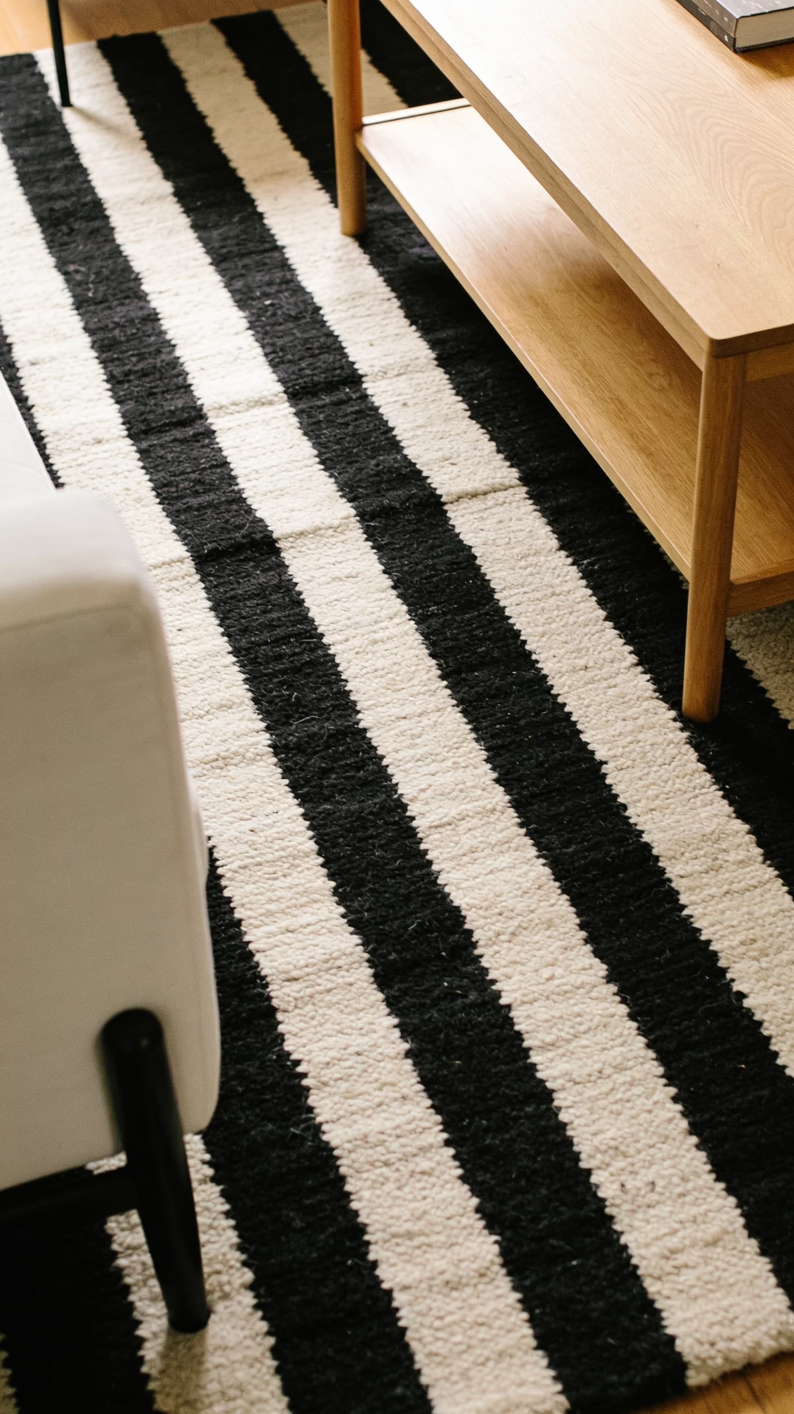 Black and white striped wool area rug under a light wood coffee table