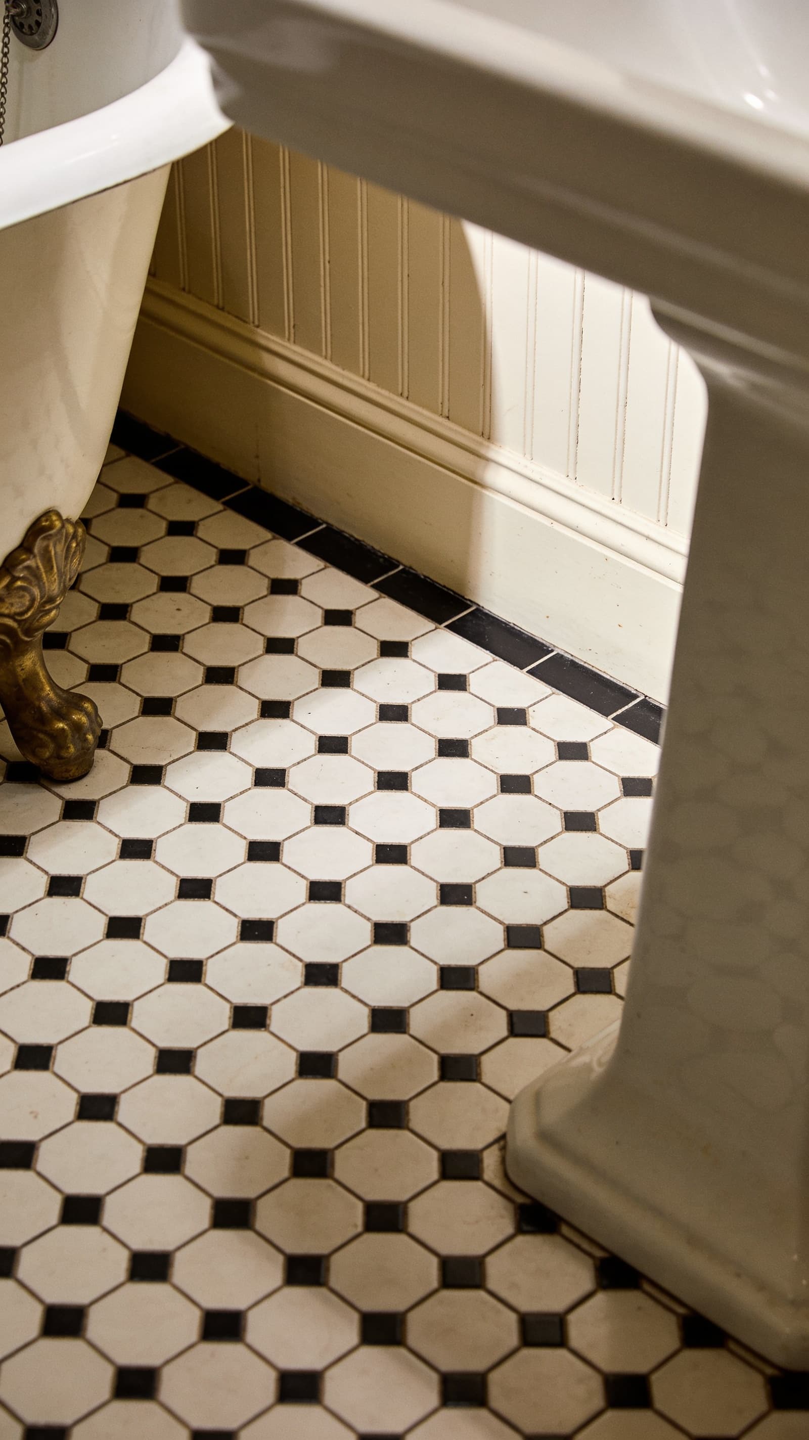Small black and white hexagonal floor tile with a thin black border in a vintage bathroom