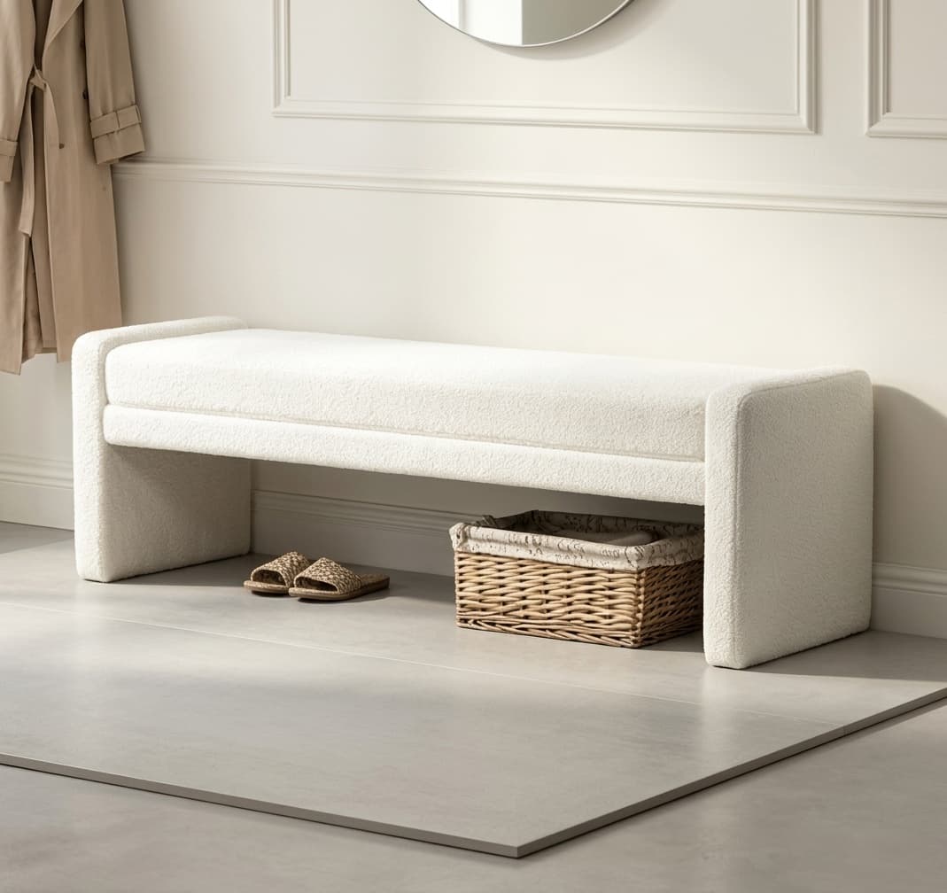 Boucle upholstered bench at the foot of a neutral bed with layered bedding